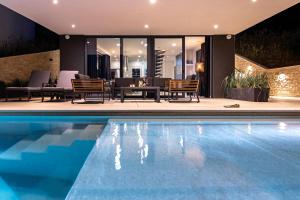 einen Pool mit Stühlen und einem Tisch neben einem Haus in der Unterkunft Villa Infinity - Luxurious seaview Villa with enchanting Pool in Kali
