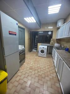 a kitchen with a refrigerator and a washing machine at Master Bed Room with Balcony Shared Apartment AUH UAE in Abu Dhabi