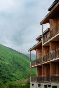 ein Gebäude mit einem grünen Hügel im Hintergrund in der Unterkunft GeoGraphy Hotels in Gudauri