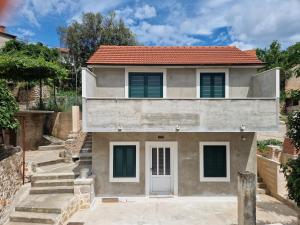 une maison avec une porte blanche et des escaliers dans l'établissement Kuća za odmor Dobrila, à Jelsa