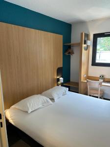 a bedroom with a large white bed and a desk at B&B HOTEL Aubagne Gémenos in Gémenos