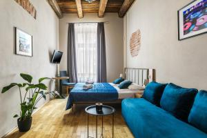sala de estar con sofá azul y cama en Aparthotel Pergamin, en Cracovia
