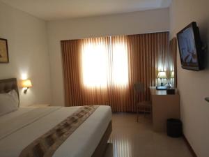 um quarto de hotel com uma cama grande e uma janela em Hotel Arjuna em Yogyakarta