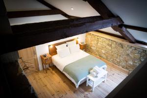 an attic bedroom with a bed and a stone wall at Les Chemins de Berdis in Montfort-en-Chalosse