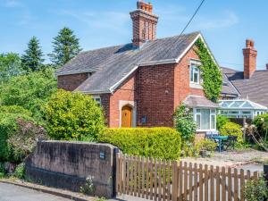 une maison en briques rouges avec une clôture en bois dans l'établissement Pass the Keys Cosy 2 bedroom cottage in rural Shropshire, à Rodington