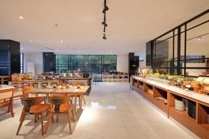 een restaurant met houten tafels, stoelen en ramen bij Metro Park View Hotel Kota Lama Semarang in Semarang