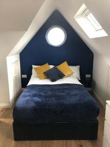 a blue bedroom with a bed with yellow pillows at Cosy Loft Apartment Just Off Vibrant Mill Rd Cb1 in Cambridge