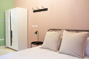 una camera da letto con un letto con cuscini bianchi e uno specchio di Three Cities Guest House a Cospicua