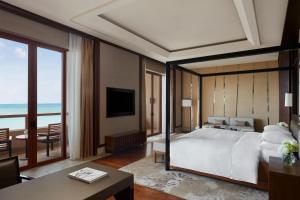 a bedroom with a bed and a view of the ocean at Haikou Marriott Hotel in Haikou