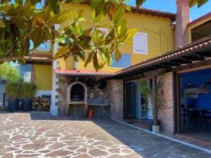 een geel huis met een bakstenen patio met een open haard bij Espectacular casa con piscina y jardín in Oruña