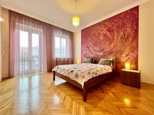 ブダペストにあるExclusive Colourful Flat in the cityのベッドルーム1室(ベッド1台付)が備わります。壁には大きな絵画が飾られています。