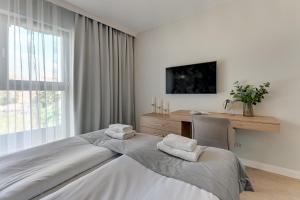 a bedroom with a bed and a desk and a window at Grano Residence Riverview - Pool, Gym & SPA by Downtown Apartments in Gdańsk
