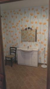 a bathroom with a sink and a chair and a mirror at il Balcone sul Monferrato in Tonco