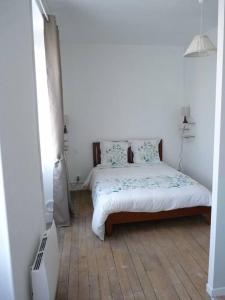 a bedroom with a bed in a white room at Des Envies et Des Songes in Saint-Amand-en-Puisaye
