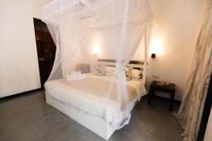 ein Schlafzimmer mit einem weißen Bett und einem Moskitonetz in der Unterkunft Beautiful Beachfront Villa - Lumi Villa in Tangalle