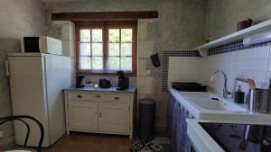 a kitchen with a white refrigerator and a sink at Gîte Galadriel - Charme et Nature in Chambon
