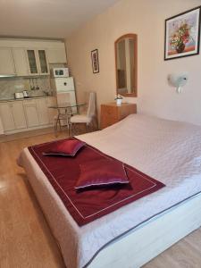 ein Schlafzimmer mit einem großen Bett und einem roten Bademantel. in der Unterkunft Apartment Prestige Fort Beach, Studio in Sweti Wlas