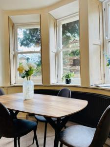 a wooden table with chairs and a vase with flowers at Restful Victorian Apartment with Garden in Bristol