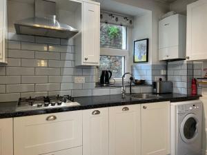 a kitchen with white cabinets and a sink and a stove at Restful Victorian Apartment with Garden in Bristol