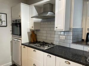 a kitchen with white cabinets and a stove top oven at Restful Victorian Apartment with Garden in Bristol
