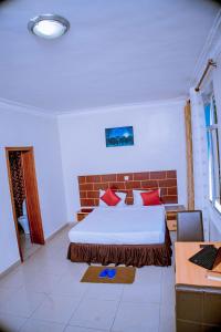 um quarto com uma cama grande e almofadas vermelhas em DANA KIGALI HOTEL em Kigali