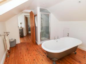 a bathroom with a bath tub on a wooden floor at The Old Stables in Newquay +33 photos
