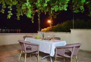 - une table avec une nappe et des chaises blanches sur la terrasse dans l'établissement Apartments Corovic, à Kotor
