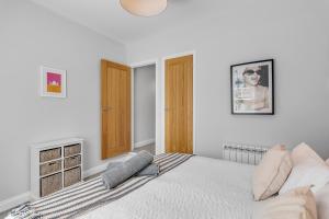 a white bedroom with a bed and a wooden door at Surrey Street Duplex in Norwich