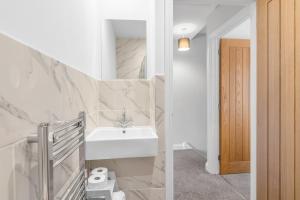 a white bathroom with a sink and a mirror at Surrey Street Duplex in Norwich