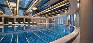 a large swimming pool with a woman standing next to it at JW Marriott Hotel Chongqing in Chongqing