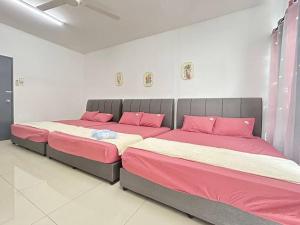 77 Mantin # U Homestay - 4Bed & 4Bath في Mantin: سريرين في غرفة ذات أغطية وردية وبيضاء