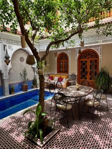 patio con tavolo e sedie sotto un albero di RIAD SHAJARA a Marrakech