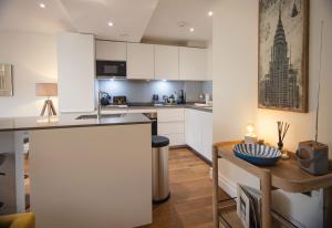 Kensington High Street One Bed في لندن: مطبخ بدولاب بيضاء وطاولة خشبية