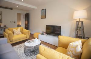 a living room with yellow furniture and a flat screen tv at Kensington High Street One Bed in London