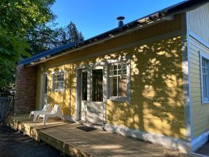 Una casa verde con dos sillas blancas en un porche de madera. en Villa Tourula, en Jyväskylä