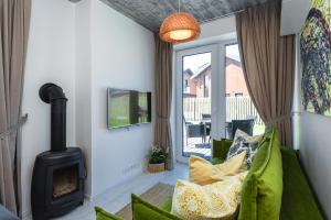 a living room with a fireplace and a green couch at Žalia Kopa apartamentai in Palanga
