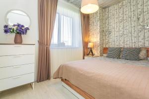 a bedroom with a bed with a dresser and a mirror at Žalia Kopa apartamentai in Palanga