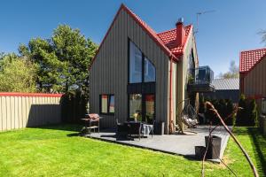 a black house with a deck in a yard at Žalia Kopa apartamentai in Palanga