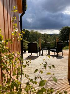 two chairs and a table on a wooden deck at River Huts, Highland River Retreat with Hot Tub in Inverness