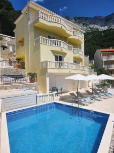 a building with a swimming pool in front of a building at Apartments - Villa Sabrina in Brela