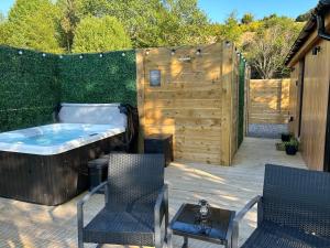 a patio with a hot tub and chairs and a fence at River Huts, Highland River Retreat with Hot Tub in Inverness