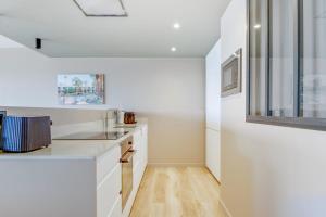 a kitchen with white cabinets and wood floors at Modern flat with terrace and garden - Le Touquet - Welkeys in Le Touquet-Paris-Plage