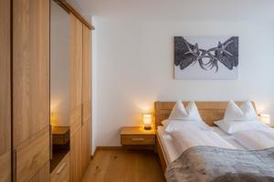 a bedroom with a bed with white sheets and two lamps at mivida - Apartment Geierkogel in Hohentauern
