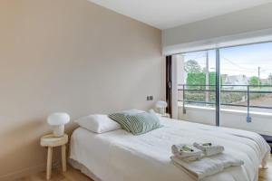 een witte slaapkamer met een groot bed en een groot raam bij Modern flat with terrace and garden - Le Touquet - Welkeys in Le Touquet-Paris-Plage