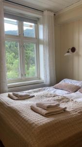a bed with two towels on it with a window at Heidal Gjestgiveri AS in Nedre Heidal