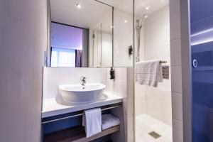 ein Bad mit einem Waschbecken und einem Spiegel in der Unterkunft Premier Inn München Messe in Haar