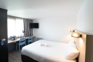ラ・ロシェルにあるHotel Inn Design La Rochelleのベッドとデスクが備わるホテルルームです。