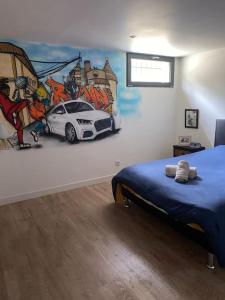 a bedroom with a painting of a car on the wall at Loft proche centre ville Hôtes habitant à l étage in Laval
