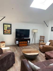 a living room with a couch and a tv at Loft proche centre ville Hôtes habitant à l étage in Laval