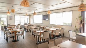 a dining room with tables and chairs and windows at Hôtel Inn Design La Rochelle in La Rochelle